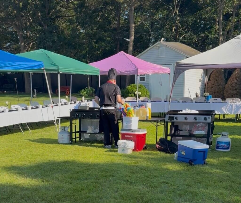 Best Hibachi chef preparing an outdoor hibachi party beside dining tables and tents