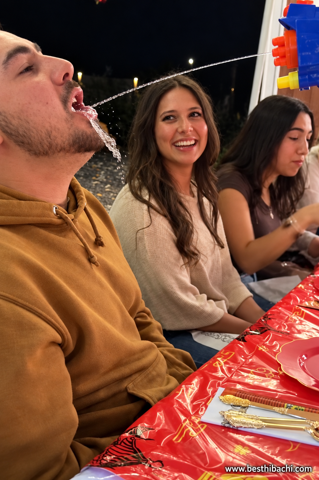 Guests laughing during a Best Hibachi party at a red-covered dining table