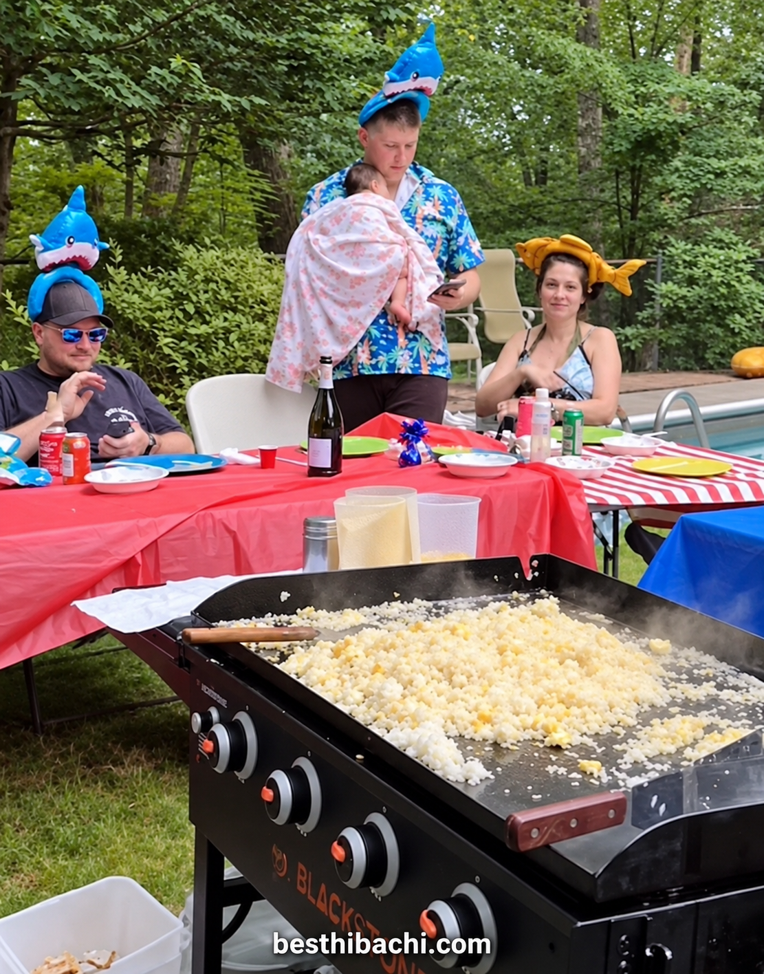 Guests wearing playful hats at a Best Hibachi backyard party beside the grill